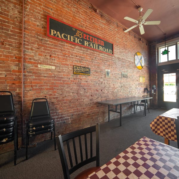 Interior of a restaurant with brick walls, checkered tablecloths, and railroad-themed decor.